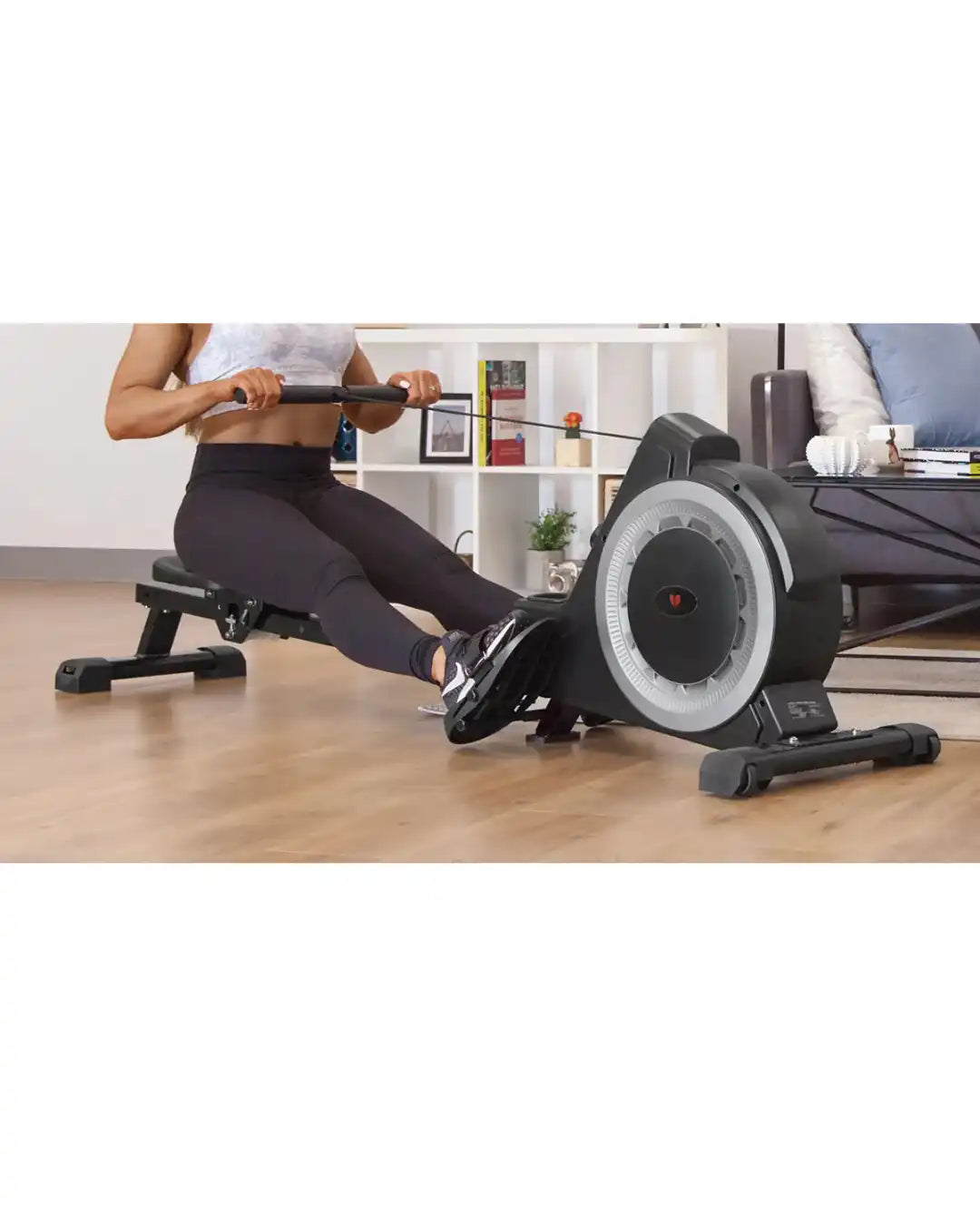 A person using a black rowing machine with a large, circular resistance unit.