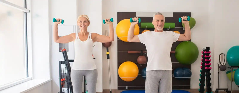 Two people exercising with dumbbells in a shoulder press motion.