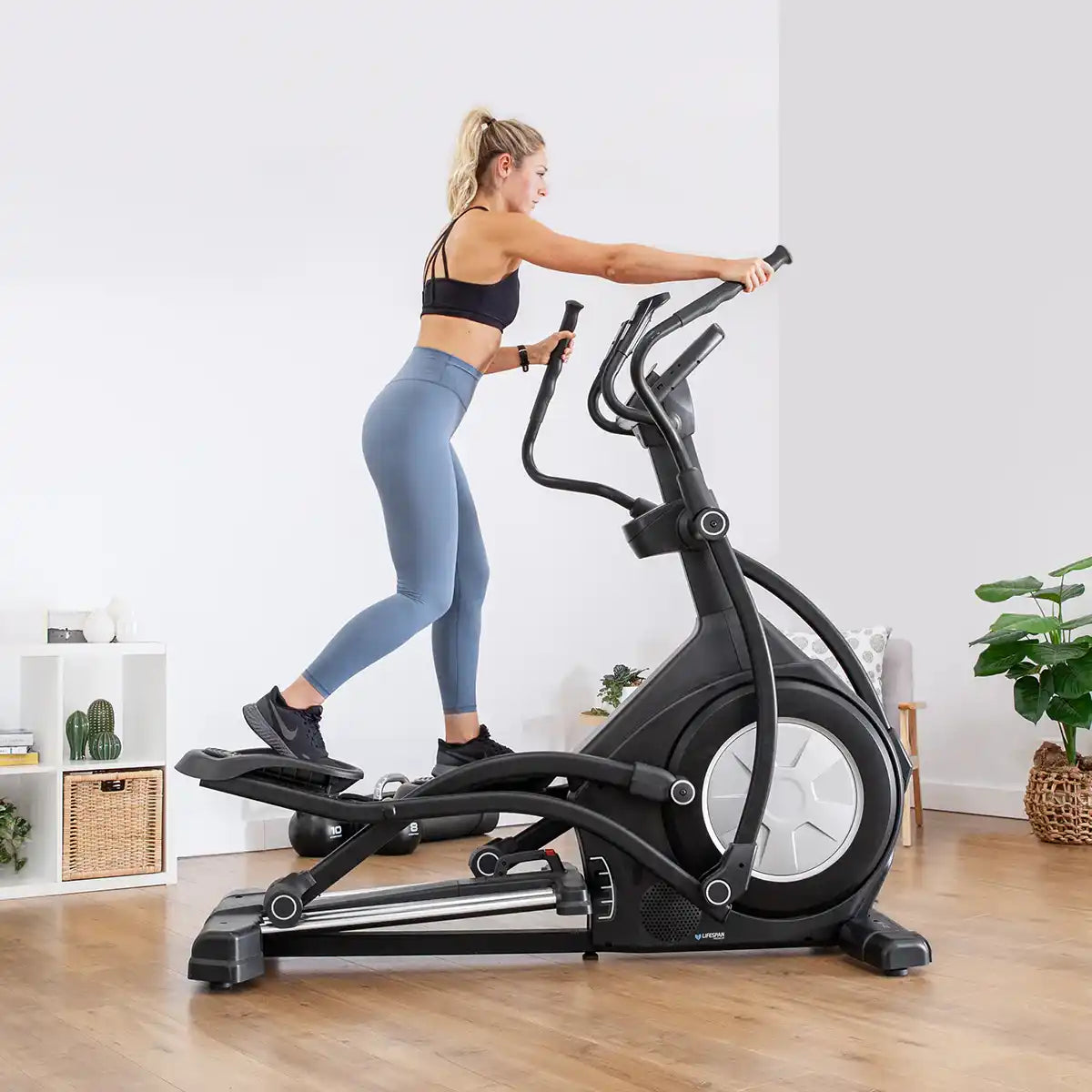 A woman exercising on a black elliptical machine.